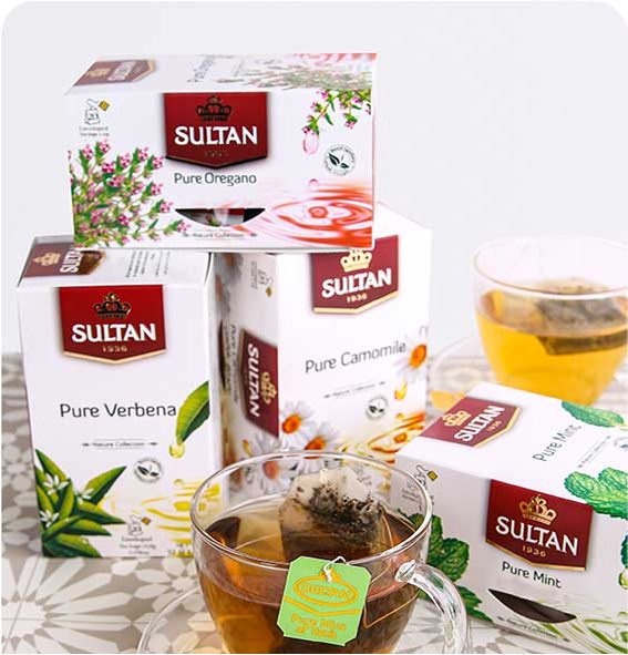 Stacked Sultan Tea boxes with a glass cup of tea and tea bag on a patterned table